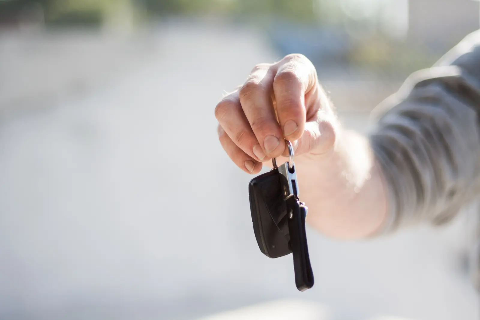 A hand holding out a set of car keys