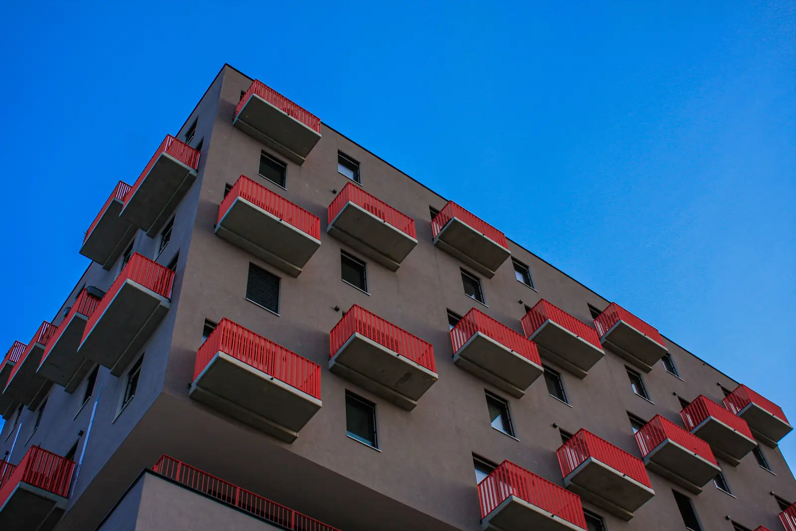 An apartment building with red balconies against a blue sky